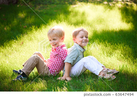 Two young boys walk and relax in the park. Two young boys walk and relax in the park. 63647494