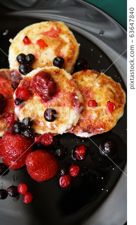 Cheese Pancakes with berries on a black plate. 63647840