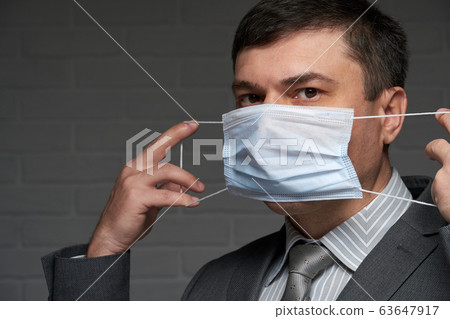 a man puts a mask on his face for antivirus a man puts a mask on his face for antivirus 63647917