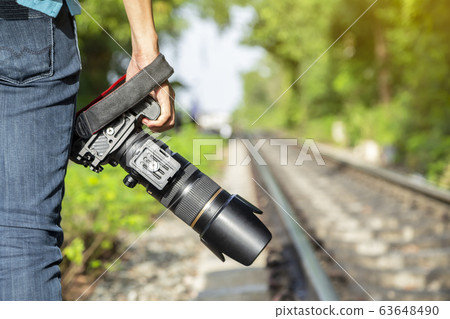 Thai photographer or traveller using a professional DSLR camera in the nature for background Thai photographer or traveller using a professional DSLR camera in the nature for background 63648490