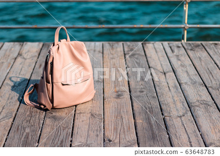 women's backpack on a wooden deck near the sea women's backpack on a wooden deck near the sea 63648783