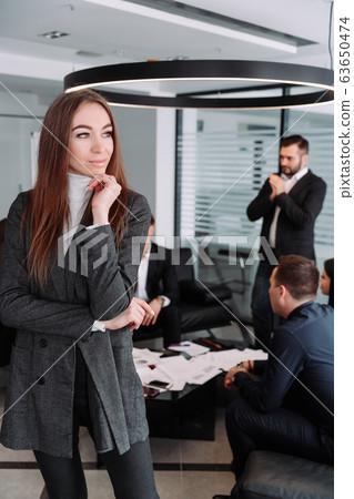 Smiling businesswoman with colleagues behind at office Smiling businesswoman with colleagues behind at office 63650474
