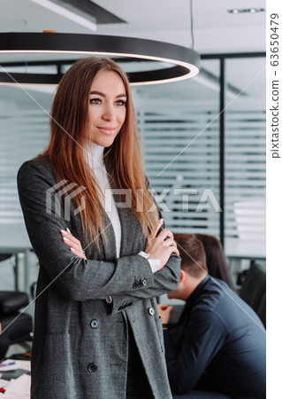 Smiling businesswoman with colleagues behind at office 63650479