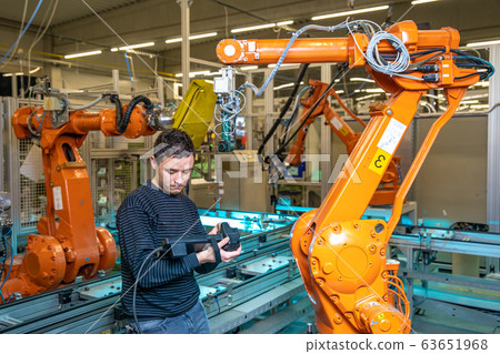 production engineer programs the robotic arms on the production line in a factory 63651968