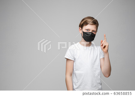 Teenage boy stands in black medical mask, portrait Teenage boy stands in black medical mask, portrait 63658855