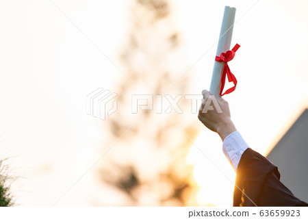 Women Student Graduate in cap and gown celebrating with certificate in hand and so proud Women Student Graduate in cap and gown celebrating with certificate in hand and so proud 63659923