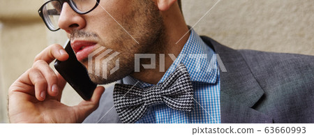 portrait of young handsome man in butterfly. he is calling someone portrait of young handsome man in butterfly. he is calling someone 63660993