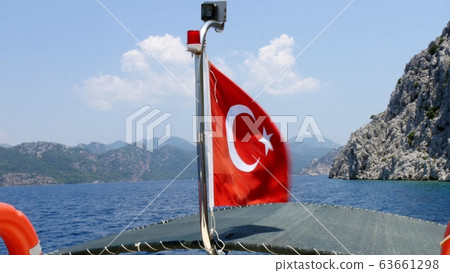 Turkish flag flapping at the back of a boat in the back part of a traditional boat. Turkish flag flapping at the back of a boat in the back part of a traditional boat. 63661298