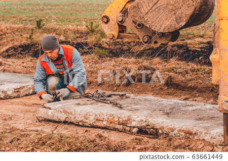 The worker unlocks the chains from the concrete The worker unlocks the chains from the concrete 63661449