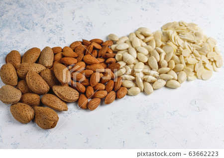 Raw fresh almonds with shell,without shelll,almond slices on grey concrete background,top view Raw fresh almonds with shell,without shelll,almond slices on grey concrete background,top view 63662223