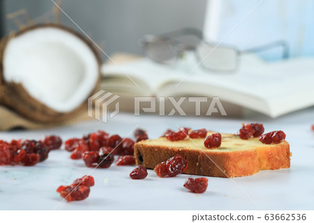 Coconut, red dry berries, slice of toast and a book on the marble 63662536