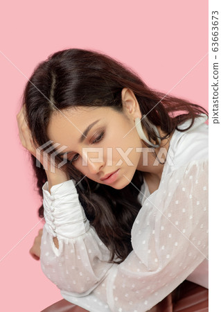 Young pretty brunette woman in a white blouse looking upset Young pretty brunette woman in a white blouse looking upset 63663673