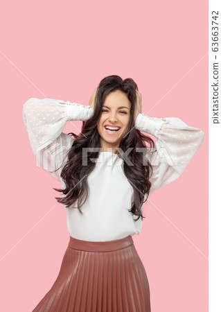 Young pretty brunette woman in a white blouse holding her head and smiling Young pretty brunette woman in a white blouse holding her head and smiling 63663742