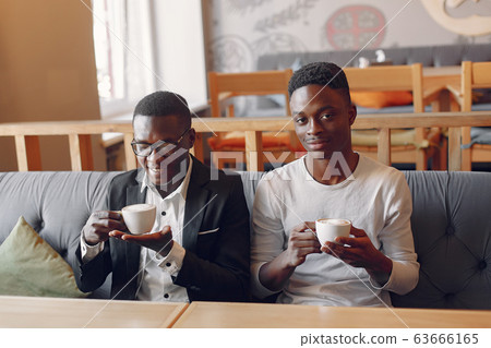 Black men sitting in a cafe and drinking a coffee 63666165