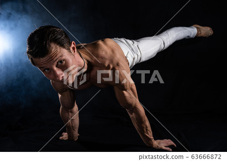 Muscular man making planche on black black background Muscular man making planche on black black background 63666872