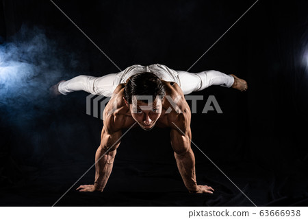 Muscular man making planche on black black background 63666938