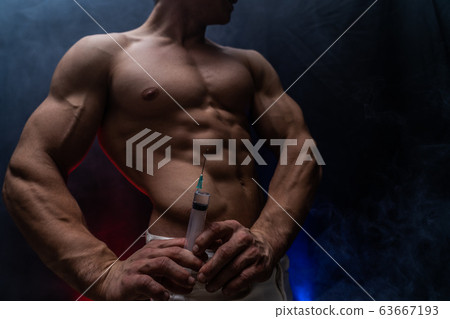 Bodybuilder holding big syringe with injection. concept of steroid in the sport and addiction Bodybuilder holding big syringe with injection. concept of steroid in the sport and addiction 63667193