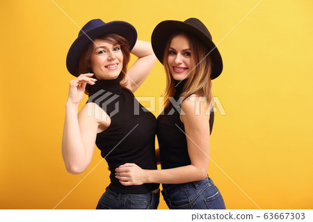 Fashion girls posing on a yellow background 63667303