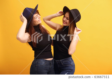 Fashion girls posing on a yellow background Fashion girls posing on a yellow background 63667311