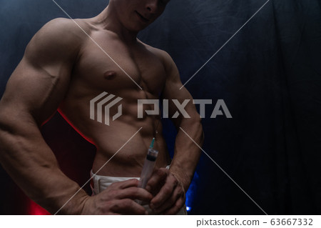 Bodybuilder holding big syringe with injection. concept of steroid in the sport and addiction  63667332