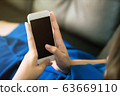 Closeup women using blank screen smartphone on black sofa at home with clipping path 63669110