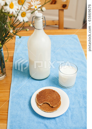 Simply stylish wooden kitchen with bottle of milk and glass on table, summer flowers camomile, healthy foog moring concept Simply stylish wooden kitchen with bottle of milk and glass on table, summer flowers camomile, healthy foog moring concept 63669676