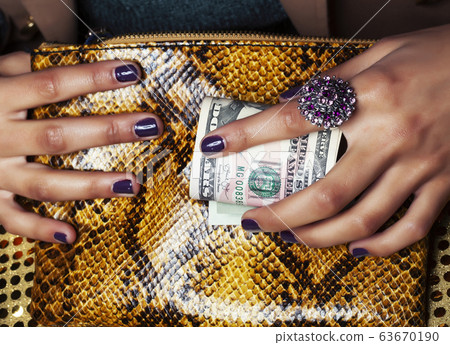 pretty fingers of african american woman holding money closeup with purse, luxury jewellery on python clutch, cash for gifts pretty fingers of african american woman holding money closeup with purse, luxury jewellery on python clutch, cash for gifts 63670190