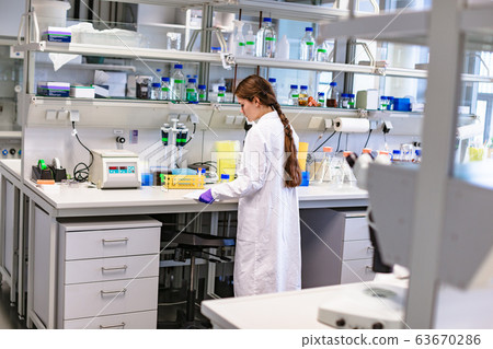 Girl scientist studying notes near lab equipment Girl scientist studying notes near lab equipment 63670286