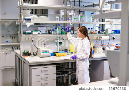 Woman scientist with test tube in hand working in 63670288