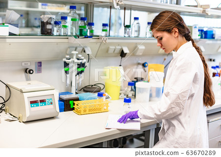 Girl scientist studying notes near lab equipment 63670289