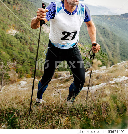 man athlete uphill mountain with trekking poles 63671491