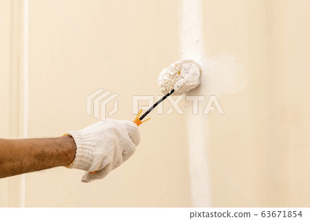 Using a roller for painting white color on the Using a roller for painting white color on the 63671854
