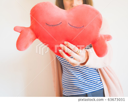 Faceless woman covering face with red heart toy Faceless woman covering face with red heart toy 63673031