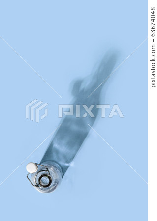 Glass bottle for water stands on a blue background, top view. Beautiful shadow with highlights 63674048