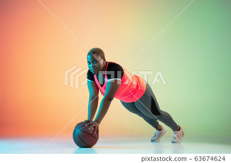 Young african-american plus size female model's training on gradient background 63674624