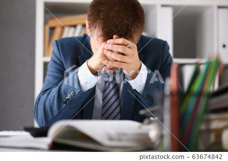 A man experiences stress and a headache in the workplace A man experiences stress and a headache in the workplace 63674842