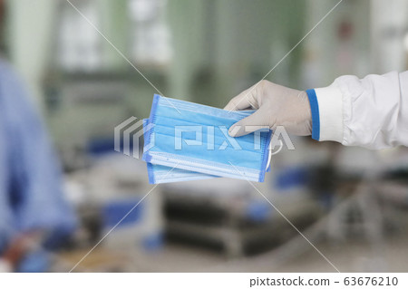 Medical masks in the hands of doctors are used for protection against germs and air pollution. Medical masks in the hands of doctors are used for protection against germs and air pollution. 63676210