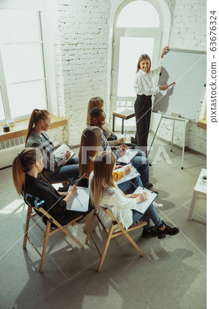 Female caucasian speaker giving presentation in hall at university or business centre workshop 63676324
