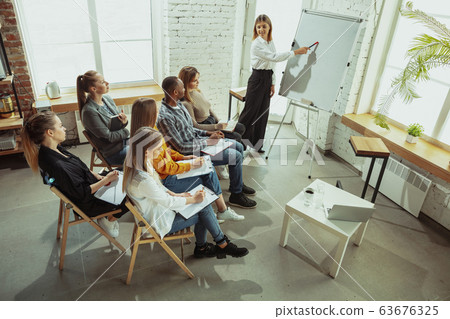 Female caucasian speaker giving presentation in hall at university or business centre workshop 63676325