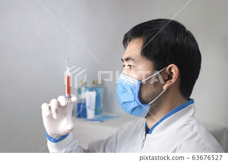 Medical vaccine syringe for medicine injection treatment holding in a hand of the doctor. 63676527