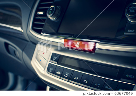 Car emergency light button on dashboard in a car. 63677049