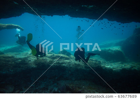 divers comes out of an underwater cave 63677689