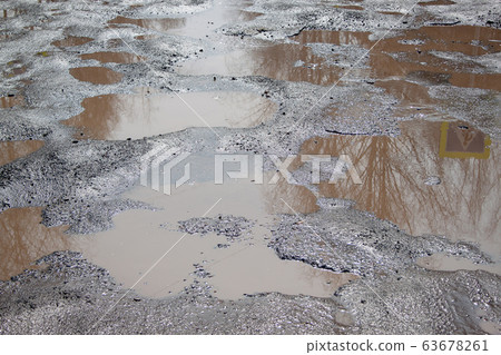 Dangerous destroyed road. Big pothole with water. 63678261