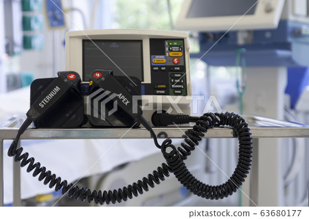 Defibrillator,  on background medical ventilator in ICU in hospital, a place where can be treated patients with pneumonia caused by coronavirus covid-19. 63680177