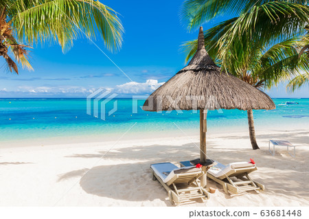 Chairs with umbrella at luxury beach with palms and blue ocean. Holiday banner 63681448