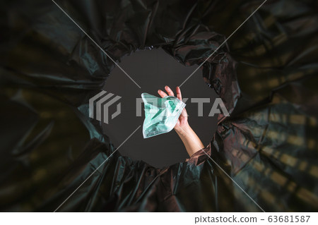 Throwing a face mask into the trash. 63681587