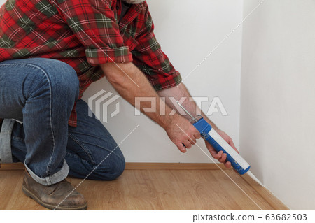 Home renovation, worker caulking batten with 63682503