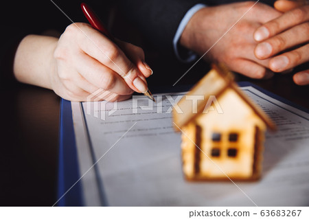Key of home on hand of bank employeer to sell house after approve loan and buyer signing in contract paper in office. 63683267