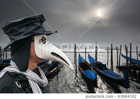 Plague doctor against gondolas during foggy day in Venice, Italy, Epidemic symbol 63684102