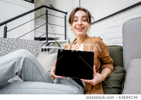 Woman with a digital tablet at home, showing screen 63684236